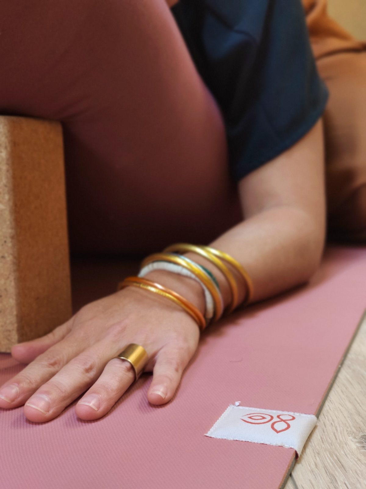 Main posée près d'une brique en liège sur un tapis de yoga