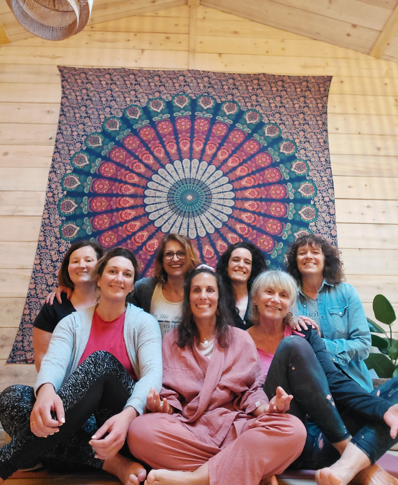 Groupe de femmes souriantes dans le chalet de retraite, tenture mandala, Vibre & Respire