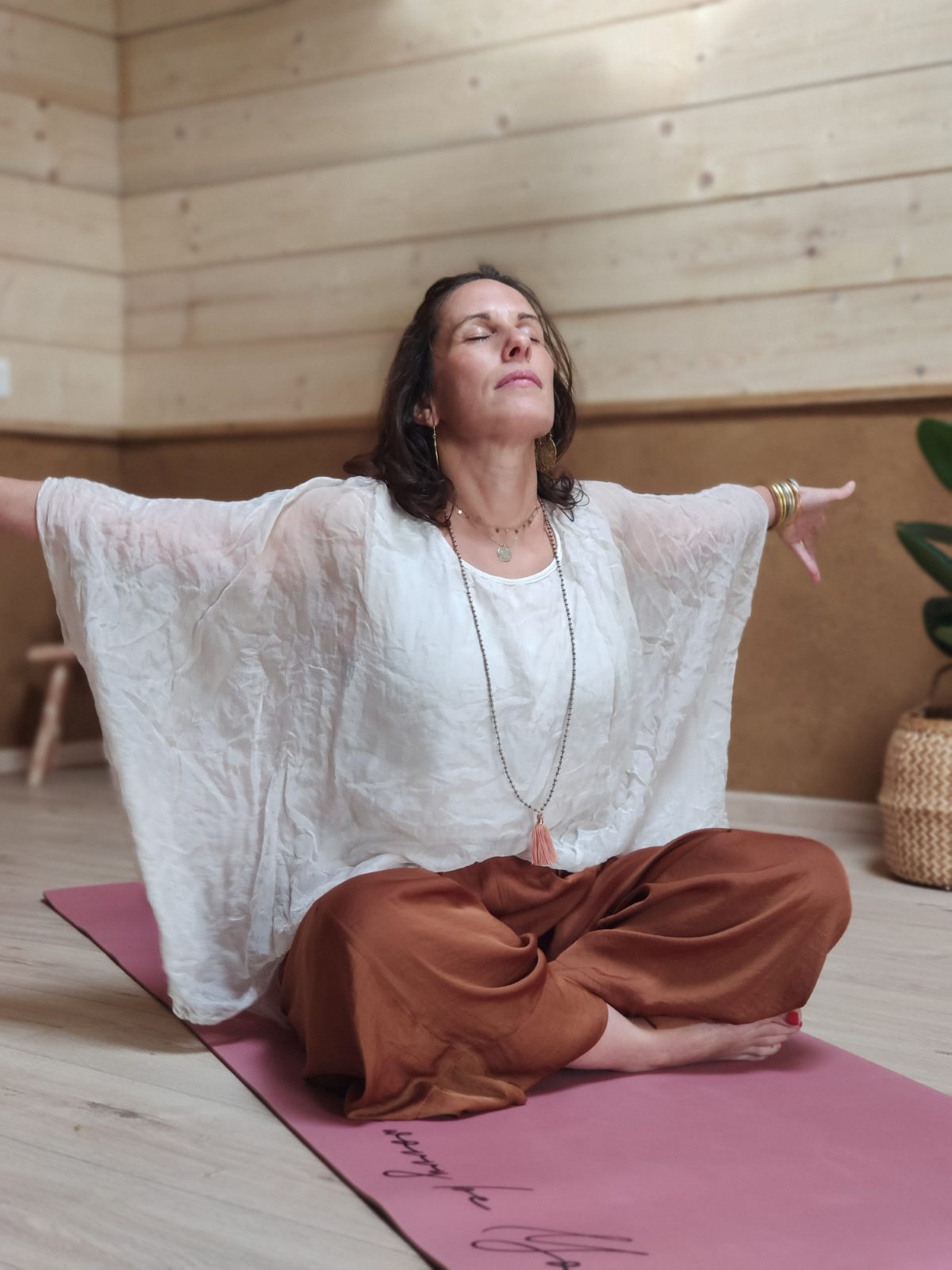 Angélique en posture de yoga, bras ouverts, dans son studio des Landes
