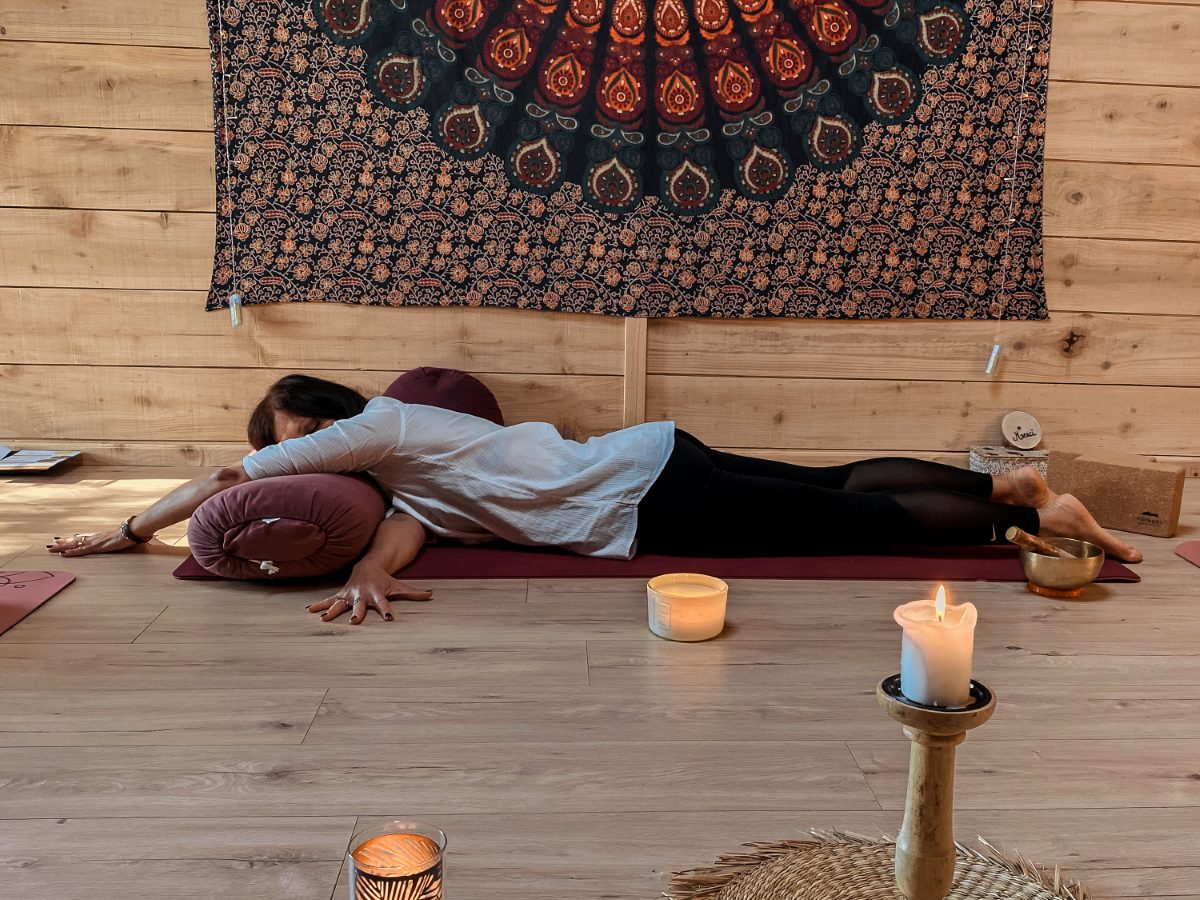 Posture restaurative soutenue par un bolster et un coussin, bougies et bol chantant, dans le studio d'Angélique