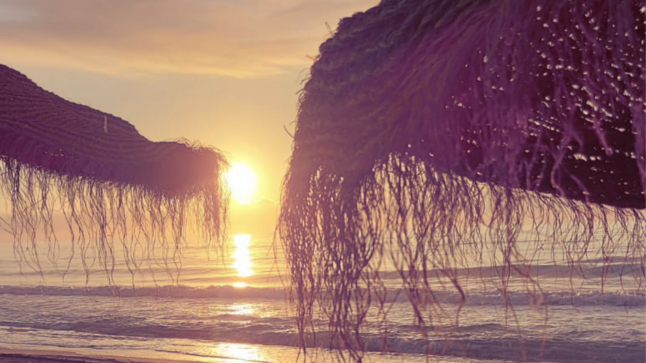 Lumière chaude d'été sur la mer au lever du soleil, entre deux parasols de paille